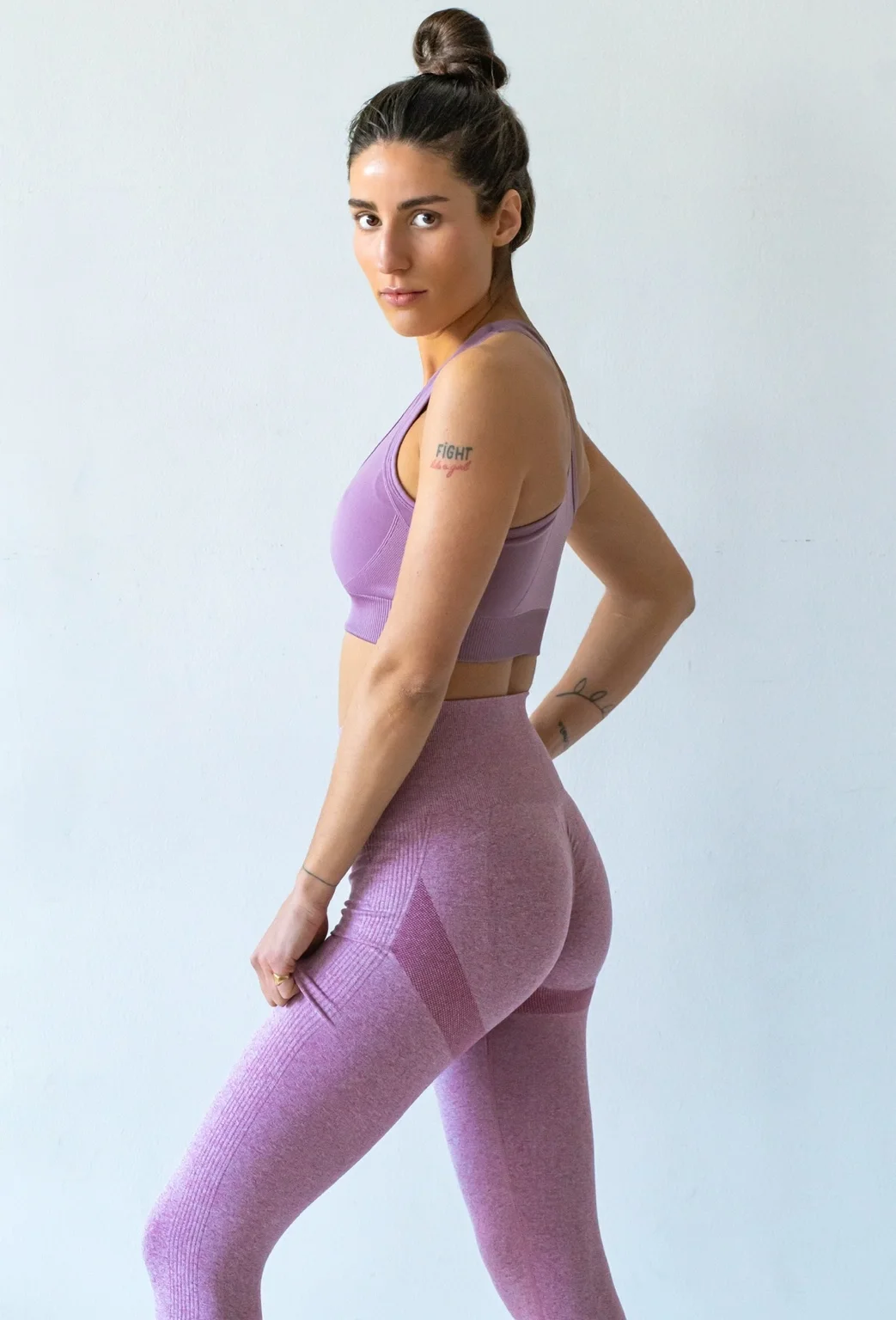 Marie Lamy en mouvement, dans une posture sportive latérale sur fond lilas.
